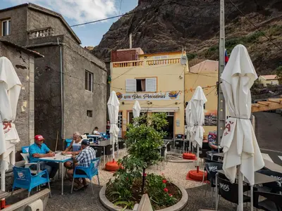 a group of people sitting at tables outside a restaurant at Apartment Blue Sea in Paul do Mar