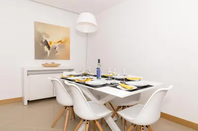 a white dining room with a white table and white chairs at Beach Condominium in Lagos