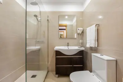 a bathroom with a toilet and a sink and a shower at White Waters Hotel in Machico