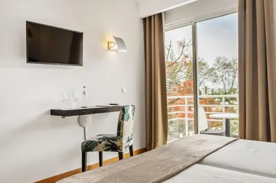 a hotel room with a bed and a desk and a window at White Waters Hotel in Machico