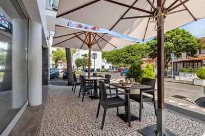 a table and chairs with umbrellas on a sidewalk at White Waters Hotel in Machico