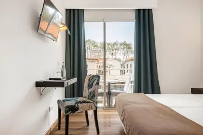 a bedroom with a bed and a desk and a window at White Waters Hotel in Machico