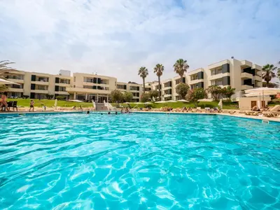 a large swimming pool with buildings in the background at Vila Baleira Suites in Porto Santo