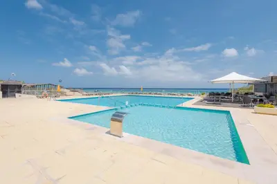 a large swimming pool with the ocean in the background at Vila Baleira Suites in Porto Santo