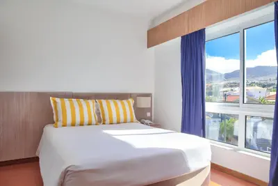 a bedroom with a bed and a large window at Hotel Praia Dourada in Porto Santo