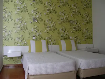 two beds in a room with a green wall at Hotel Praia Dourada in Porto Santo