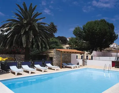 a swimming pool with chairs and a palm tree at Hotel Praia Dourada in Porto Santo