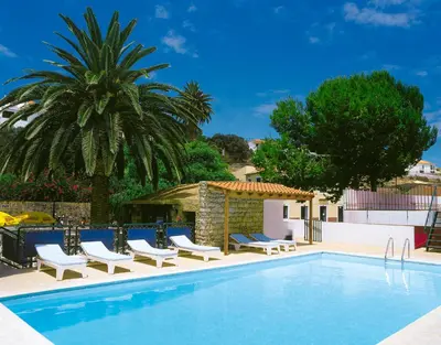 a swimming pool with chairs and a palm tree at Hotel Praia Dourada in Porto Santo