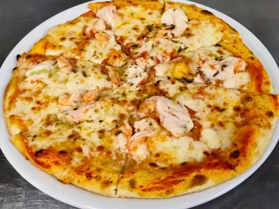 a pizza with shrimp on a plate on a table at Quinta da Floresta – Santo António Villas, Golf & Spa in Budens