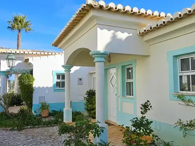 a house with a blue door and a palm tree at Quinta da Floresta – Santo António Villas, Golf & Spa in Budens