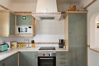 a kitchen with green cabinets and a stove top oven at Quinta da Floresta – Santo António Villas, Golf & Spa in Budens