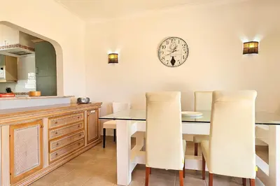 a kitchen with a dining table and a clock on the wall at Quinta da Floresta – Santo António Villas, Golf & Spa in Budens