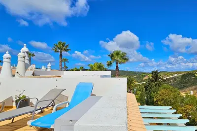 a view from the roof of a house with blue chairs at Quinta da Floresta – Santo António Villas, Golf & Spa in Budens