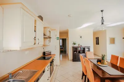 a kitchen with white cabinets and a table and chairs at Casa do Pocinho in Raposeira