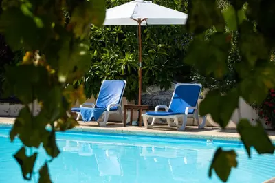 two blue chairs and an umbrella next to a pool at OurMadeira - Casa do Feitor in Funchal