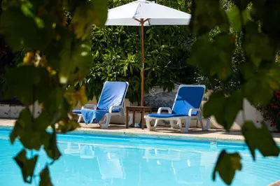 two blue chairs and an umbrella next to a pool at OurMadeira - Casa das Vinhas in Funchal
