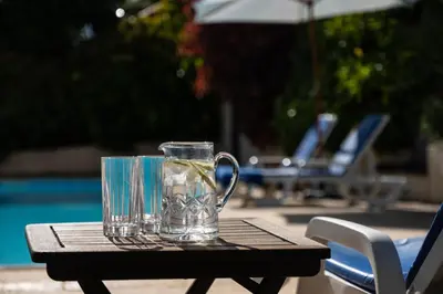 a glass pitcher sitting on a table next to a pool at OurMadeira - Casa das Vinhas in Funchal