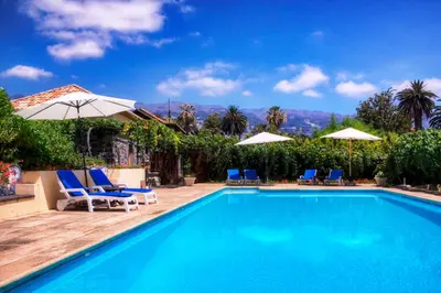 a swimming pool with blue chairs and umbrellas at OurMadeira - Casa das Vinhas in Funchal