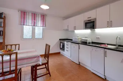 a kitchen with white cabinets and a table with chairs at OurMadeira - Loja da Lenha in Funchal