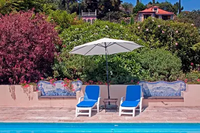 two chairs and an umbrella next to a pool at OurMadeira - Loja da Lenha in Funchal