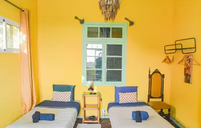 two beds in a yellow room with a window at La Maison ZiaZen in Porto da Cruz