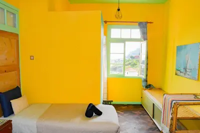 a yellow room with a bed and a window at La Maison ZiaZen in Porto da Cruz