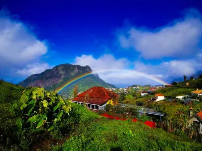 a rainbow over a town with a mountain at La Maison ZiaZen in Porto da Cruz
