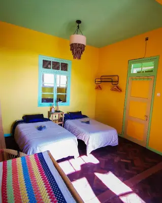 two beds in a room with yellow walls at La Maison ZiaZen in Porto da Cruz