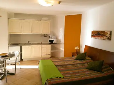 a bedroom with a bed and a table and a kitchen at Porto Mos Residence in Lagos