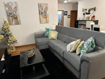 a living room with a gray couch and a christmas tree at Zeza´s apartament in Calheta