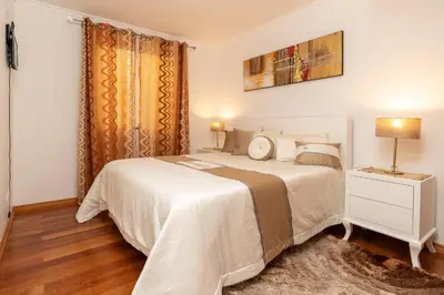 a bedroom with a large white bed and a night stand at Zeza´s apartament in Calheta