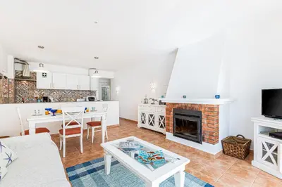 a living room with a fireplace and a table at Casa do Coral - Praia da Luz in Luz