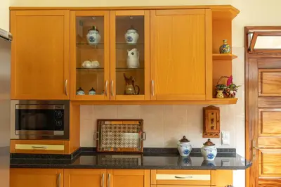 a kitchen with wooden cabinets with vases and a microwave at Casa Fatima in Funchal