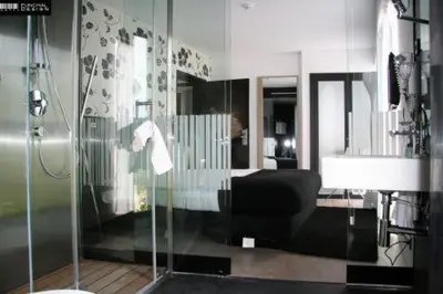 a bathroom with a glass shower with a black chair at Funchal Design Hotel in Funchal