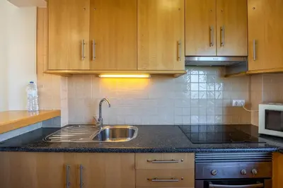 a kitchen with a sink and wooden cabinets at Pontalaia Apartamentos Turísticos in Sagres