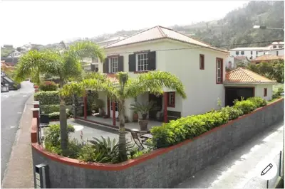 a house with palm trees in front of a street at Moradia Ponte de Pedra in São Vicente