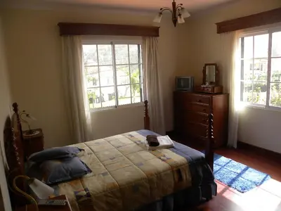 a bedroom with a bed and a dresser and two windows at Moradia Ponte de Pedra in São Vicente