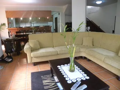 a living room with a couch and a table with remote controls at Moradia Ponte de Pedra in São Vicente