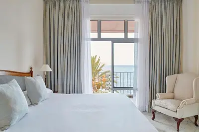 a bedroom with a large bed and a window with the ocean at Reid's Palace, A Belmond Hotel, Madeira in Funchal