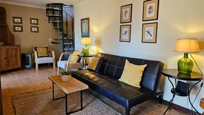 a living room with a black leather couch at Refúgio da Ribeira in Porto Moniz