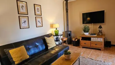 a living room with a leather couch and a tv at Refúgio da Ribeira in Porto Moniz