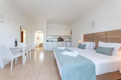 a bedroom with a bed and a table and a kitchen at Atalaia Sol Aparthotel - tennis & heated pool in winter in Lagos