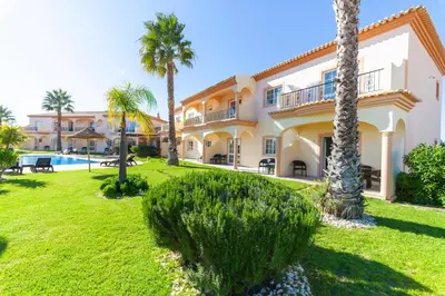 a villa with a swimming pool and palm trees at Atalaia Sol Aparthotel - tennis & heated pool in winter in Lagos