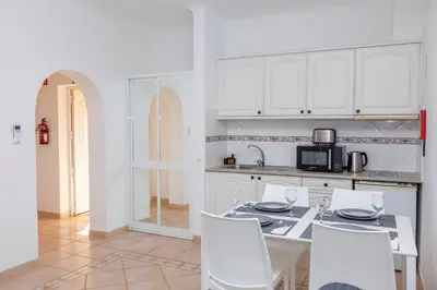 a kitchen with white cabinets and a table and chairs at Atalaia Sol Aparthotel - tennis & heated pool in winter in Lagos
