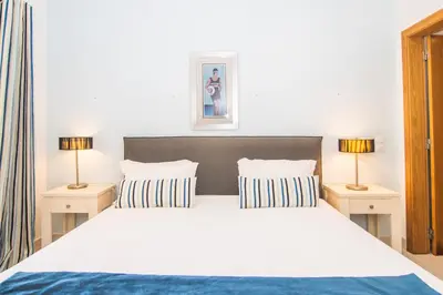 a bedroom with a large white bed with two lamps at The View – Santo António Villas, Golf & Spa in Salema