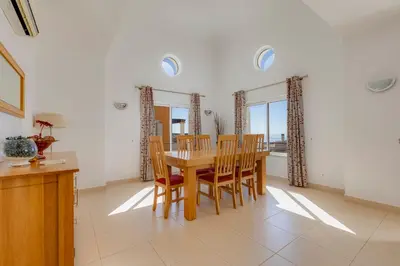a dining room with a wooden table and chairs at The View – Santo António Villas, Golf & Spa in Salema