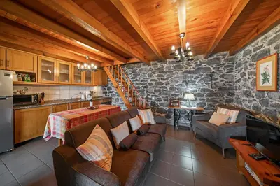 a living room with couches and a stone wall at Refúgio da Serra - By WeHost in Arco da Calheta
