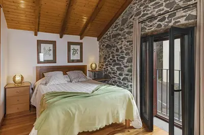 a bedroom with a bed and a stone wall at Refúgio da Serra - By WeHost in Arco da Calheta