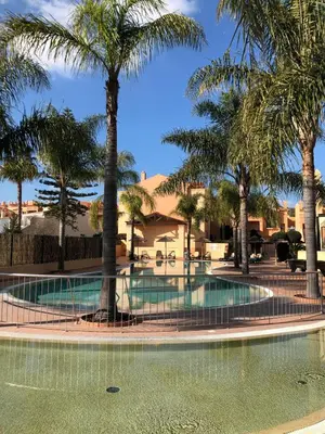 a swimming pool with palm trees in front of a building at Rother Praia da Luz Luxury Apartment in Luz