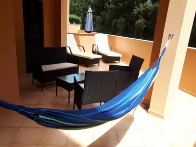 a hammock on a balcony with chairs and tables at Rother Praia da Luz Luxury Apartment in Luz